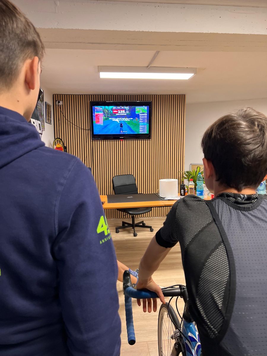 Due giovani atleti seguono l'allenamento sui rulli davanti allo schermo