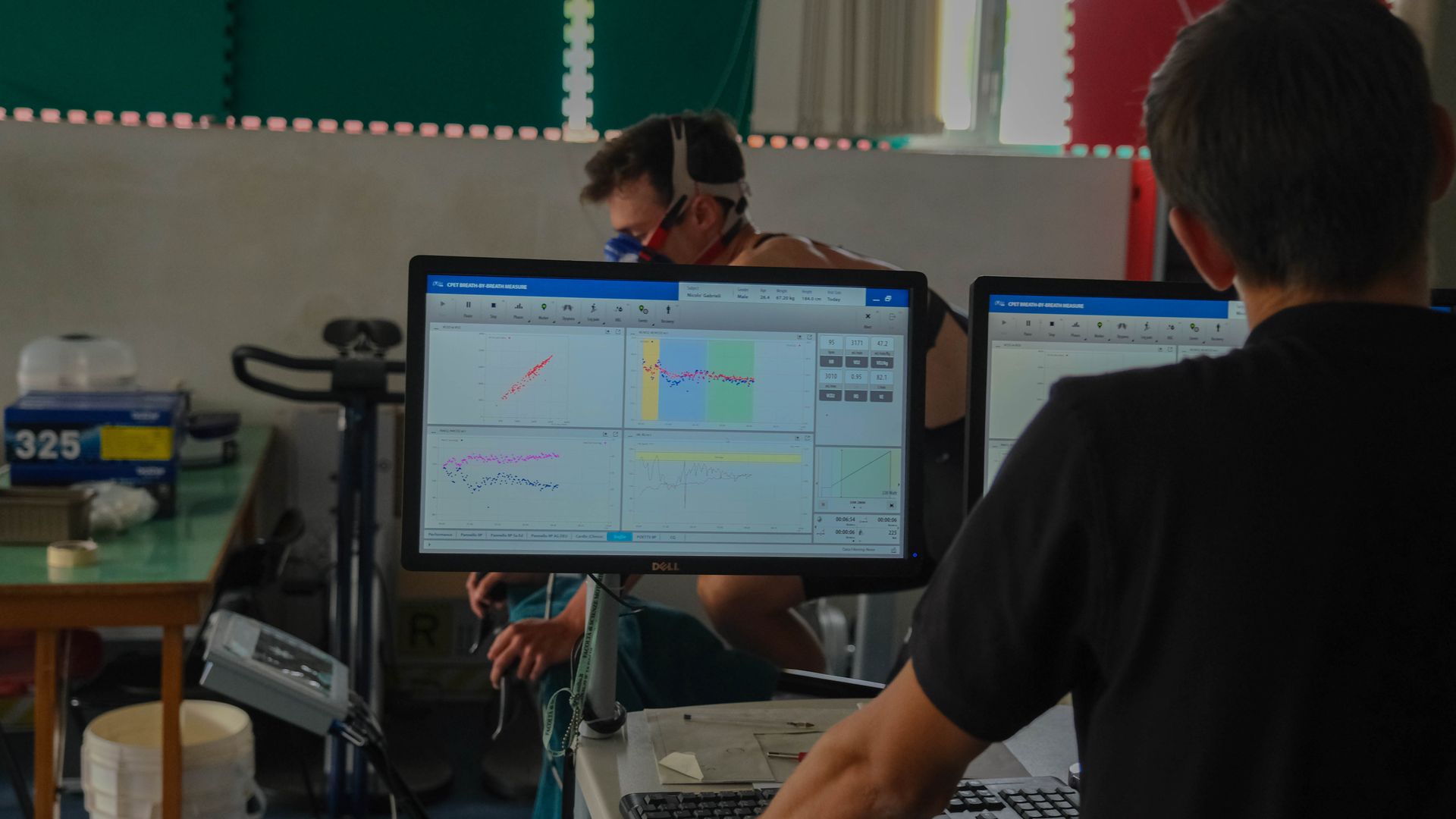 Lorenzo Elipanni legge le curve del test sui monitor del laboratorio mentre l'atleta pedala con la maschera